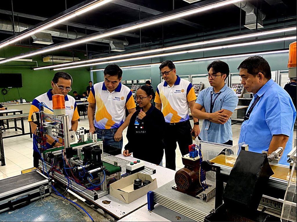 President Reginald Yu and the Club delegation tour the Dualtech workshops, where trainees operate machinery and install electrical systems.