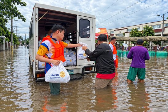 Members unload relief goods straight into the flooded community and carry each bag by hand.