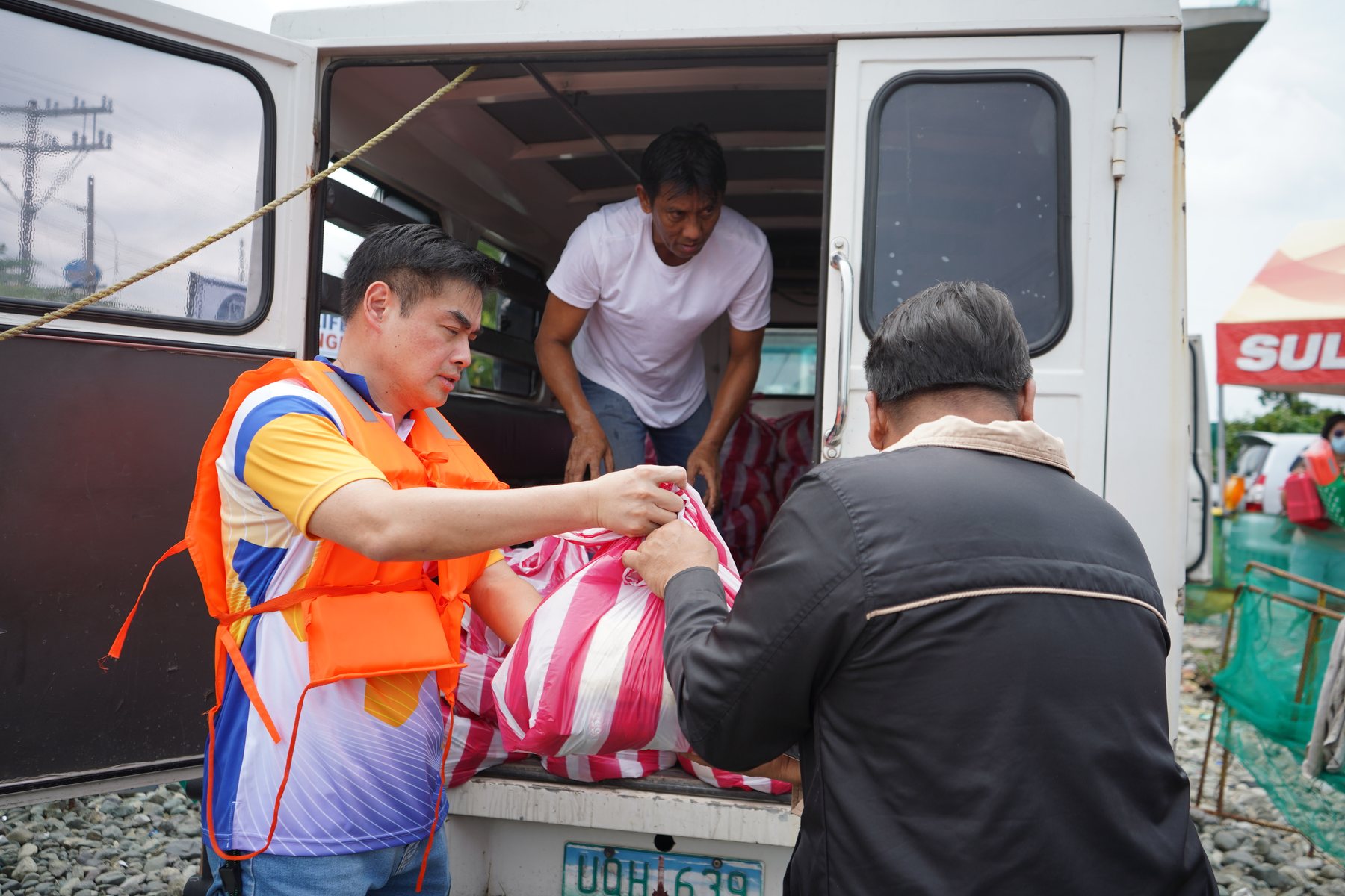 President Reginald Yu, in a life vest, passes relief bags from a van to volunteers who load them onto boats for flood-hit barangays in Calumpit, Bulacan, September 2026
